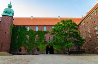 Avlu içinde Stockholm City Hall (Stadshuset) Nobel Ödülü ziyafet mahkemelerinin ve Belediye Meclisi bina Ivy ile kaplı tuğla duvarlar, döşenmiş çatı, kule, açık mavi gökyüzü, İsveç ile yeşil ağaç