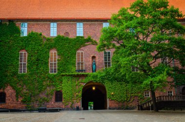 Avlu içinde Stockholm City Hall (Stadshuset) Ivy ile bina tuğla duvarlar kapalı ve Belediye Meclisi ve Nobel Ödülü ziyafet ve yeşil ağaç, İsveç yeri evler çatı kiremit