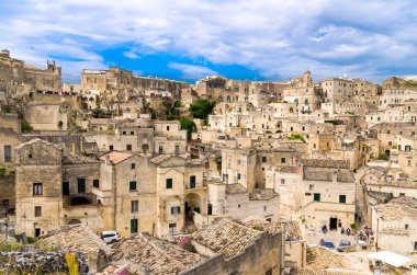 Sassi di Matera tarihi panoramik manzaralı Sasso Caveoso kaya mağara evlerin önünde mavi gökyüzü ve beyaz bulutlar, Unesco Dünya Mirası, Basilicata, Güney İtalya eski antik şehrin merkezi