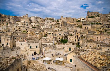 Sassi di Matera tarihi panoramik manzaralı Sasso Caveoso kaya mağara evlerin önünde mavi gökyüzü ve beyaz bulutlar, Unesco Dünya Mirası, Basilicata, Güney İtalya eski antik şehrin merkezi