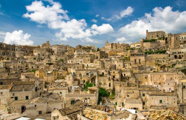 Sassi di Matera tarihi panoramik manzaralı Sasso Caveoso kaya mağara evlerin önünde mavi gökyüzü ve beyaz bulutlar, Unesco Dünya Mirası, Basilicata, Güney İtalya eski antik şehrin merkezi