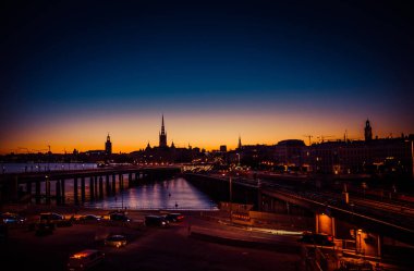 Stockholm cityscape manzarası göl Malaren Gamla Stan'da köprüden günbatımı, alacakaranlık, alacakaranlık ve mavi turuncu gökyüzü, İsveç ile Riddarholmen kilise kulesi, City Hall Stadshuset Kulesi, silüeti