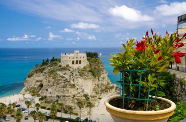 Kırmızı çiçek saksı bulanık Manastırı kutsal kilise Santa Maria dell ile Isola kaya, Tiren Denizi, mavi gökyüzü beyaz bulutların üstüne Arkaplan, Tropea kasaba, Calabria, Güney İtalya