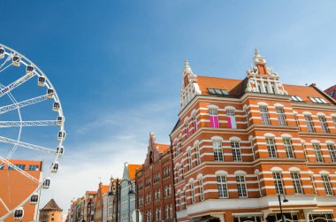 Büyük dönme dolap, geleneksel tipik turuncu binalar ve kule Brama Stagiewna mavi gökyüzü arka plan, Gdansk, Pomerania, Polonya