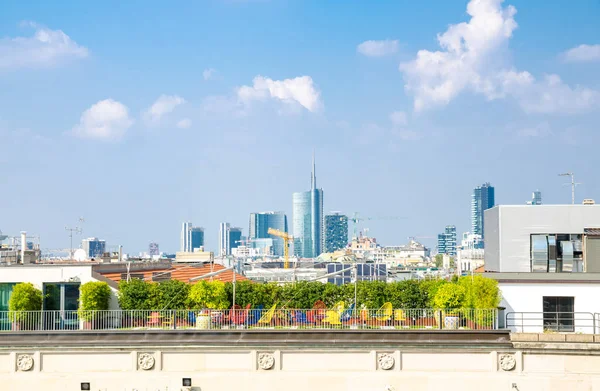 Top aerial view of Milan city centre skyscrapers from roof of famous Duomo di Milano Cathedral with blue sky white clouds, Lombardy, Italy