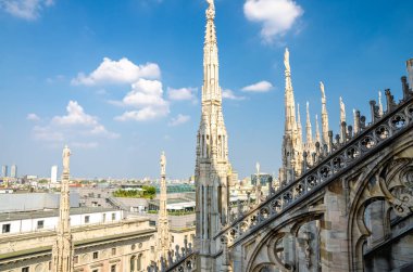 Ünlü Duomo di Milano Katedrali 'nin çatısındaki beyaz mermer heykeller ve mavi gökyüzü bulutları, Lombardy, İtalya
