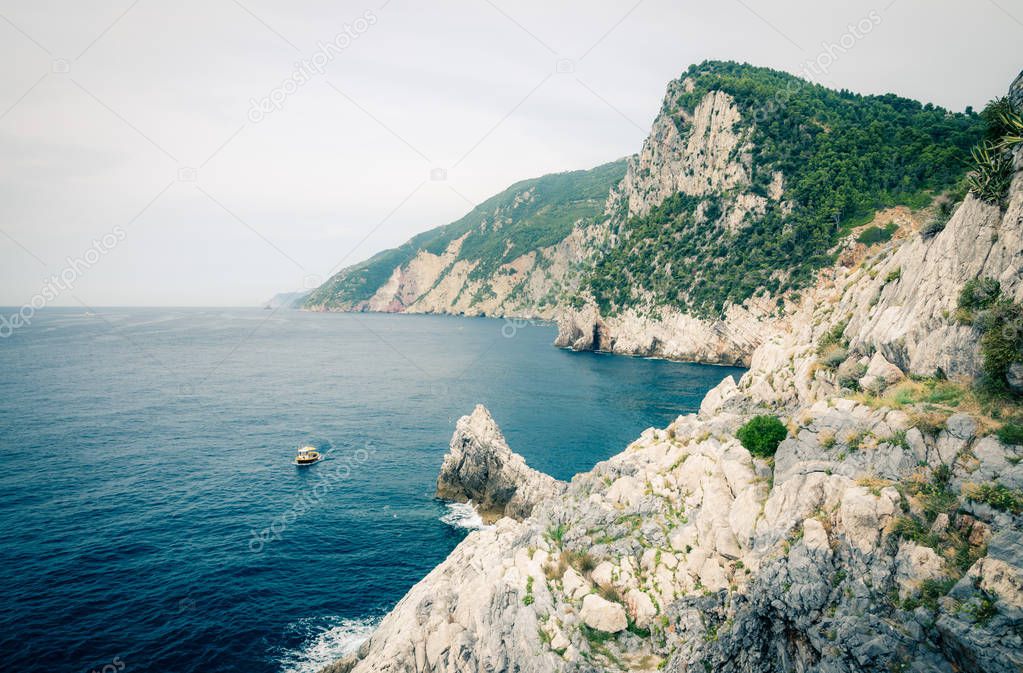 Grotta di Lord Byron with blue water, coast with rock cliff, yellow boat and blue sky near Portovenere town, Ligurian sea, Riviera di Levante, National park Cinque Terre, La Spezia, Liguria, Italy
