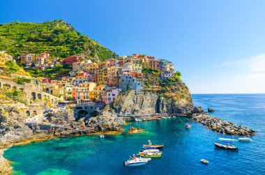 Milli park Cinque Terre Manarola geleneksel tipik İtalyan köyü, kayalık üzerinde renkli çok renkli binalar evler, su balıkçı tekneleri, mavi gökyüzü arka plan, La Spezia, Liguria, İtalya