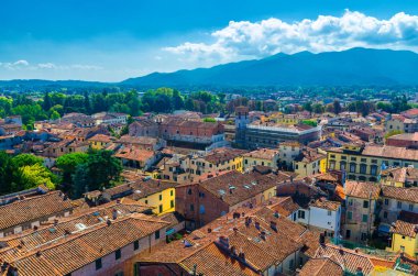 Eski binalar, tipik turuncu terakota karo çatılar ve dağ sırası, tepeler, mavi gökyüzü beyaz bulutlar arka plan, Toskana, İtalya ile tarihi merkezi ortaçağ kenti Lucca havadan üst panoramik görünümü