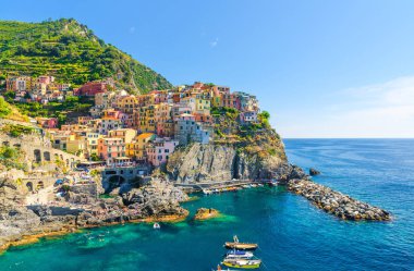 Milli park Cinque Terre Manarola geleneksel tipik İtalyan köyü, kayalık üzerinde renkli çok renkli binalar evler, su balıkçı tekneleri, mavi gökyüzü arka plan, La Spezia, Liguria, İtalya