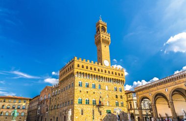 Floransa şehrinin tarihi merkezinde Piazza della Signoria meydanında saat ve Loggia dei Lanzi ile çan kulesi ile Palazzo Vecchio sarayı, mavi gökyüzü beyaz bulutlar, Toskana, İtalya