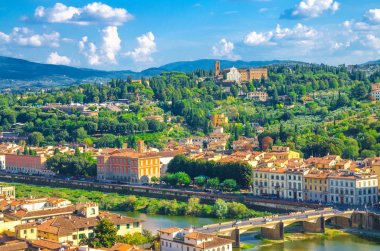 Abbazia di San Miniato al Monte ile yeşil tepelerin üst hava panoramik görünümü, Arno nehri üzerindeki köprüler, mavi gökyüzü beyaz bulutlar arka plan, Floransa şehir, Toskana, İtalya