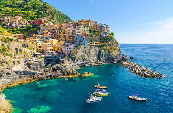 Milli park Cinque Terre Manarola geleneksel tipik İtalyan köyü, kayalık üzerinde renkli çok renkli binalar evler, su balıkçı tekneleri, mavi gökyüzü arka plan, La Spezia, Liguria, İtalya