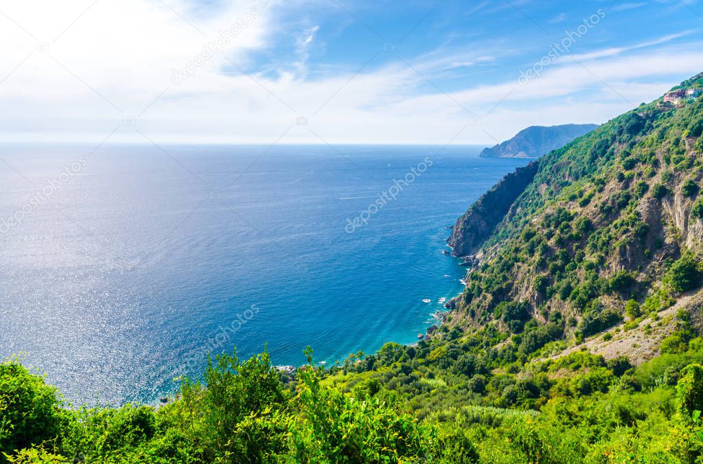 Aerial top panoramic view of green hills, rocks, cliffs and Gulf of Genoa, Ligurian Sea, coastline of Riviera di Levante, National park Cinque Terre, blue sky copy space, La Spezia, Liguria, Italy