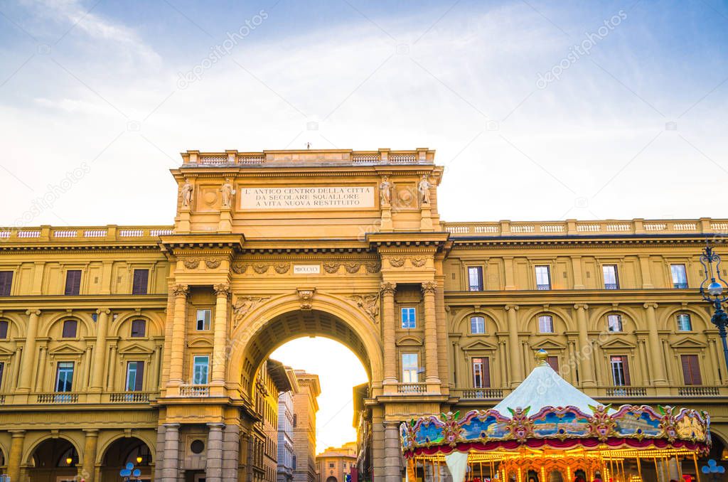 Arch between buildings and Vintage carousel on Piazza della Repubblica Republic square in historical centre of Florence city, blue sky white clouds, Tuscany, Italy