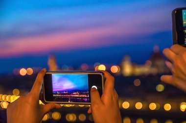 Alacakaranlıkta cep telefonu ekranı ile Duomo ile Floransa şehrinin üst hava panoramik akşam görünümü. Parmaklar cep telefonu tutmak ve gece şehir ışıkları fotoğraf yapmak. Toskana, İtalya