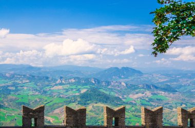 Vadi, yeşil tepeler, alanları ve mavi gökyüzü beyaz bulutlar arka plan ve meronlar ile taş kale duvar ile Cumhuriyet San Marino banliyö ilçe köyleri ile Hava üst panoramik manzara