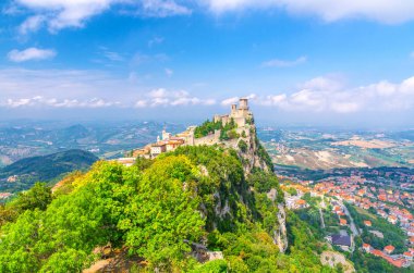 San Marino Prima Torre Guaita 'nın ilk kalesi Titano Dağı' nda tuğla duvarları olan yeşil ağaçlarla kaplı kaya, gökyüzü panoramik manzara vadisi ve banliyö tepeleri.