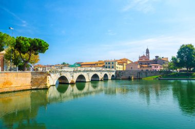Marecchia nehir suyu üzerinde ünlü taş kemer Tiberius köprü Ponte di Tiberio Augustus, mavi gökyüzü arka plan ile tarihi turistik şehir merkezi Rimini eski binalar evler, Emilia-Romagna, İtalya