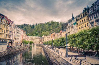 Karlovy Vary Carlsbad tarihi şehir merkezi, Tepla Nehri 'nin merkez seti çeşmeleri, renkli güzel binalar, Slavkov Ormanı tepeleri yeşil ağaçlar, Batı Bohemya, Çek Cumhuriyeti