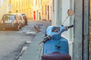 Brescia, İtalya, 11 Eylül 2019: Dar İtalyan boş caddesinde klasik mavi scooter motosiklet Vespa, şehrin eski binaları, tipik araba geçmişi, tarihi şehir merkezi, Lombardy