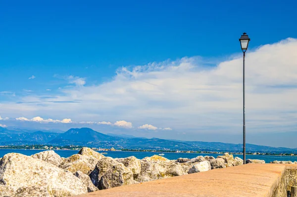 Vista desde el muelle de piedra del lago Garda con la cordillera del Monte Baldo y la península de Sirmione —  Fotos de Stock