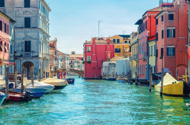 Dar su kanalı Vena ile Chioggia şehri eski renkli binalar ve tuğla köprü arasında demirlemiş tekneler ile yaz günü mavi gökyüzü arka planı, Veneto Bölgesi, Kuzey İtalya