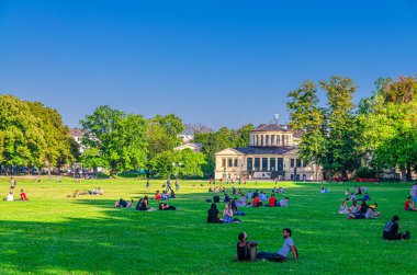 Bonn, Almanya, 23 Ağustos 2019: Akademik Sanat Müzesi arka planında, Kuzey Ren-Vestfalya bölgesinde Hofgarten bahçesinin çimlerinde dinlenen gençler
