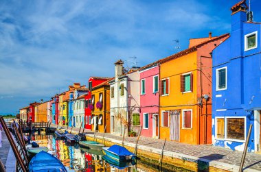 Burano adasının renkli evleri. Balıkçı tekneleri ve ahşap köprüsü olan dar su kanalının fondamenta dolgusu üzerinde çok renkli binalar, Venedik Bölgesi, Kuzey İtalya