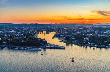 Koblenz tarihi şehir merkezinin havadan panoramik görüntüsü ve Ren ve Moselle nehirlerine katılması, ufukta muhteşem renkli turuncu günbatımının akşam alacakaranlığı görüntüsü, Rhineland-Palatinate durumu.