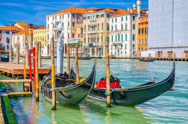 Venedik tarihi şehir merkezinde Venedik mimarisi renkli binalarla dolu Grand Canal su yolunun ahşap rıhtımına demirlemiş Gondol geleneksel tekneleri. Veneto Bölgesi, Kuzey İtalya.