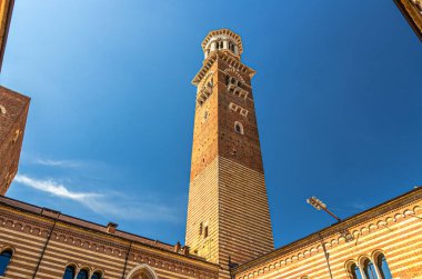 Torre dei Lamberti saat kulesi Verona şehir tarihi merkezinde Piazza Delle Erbe meydanındaki Palazzo della Ragione saray binası, Eski Pazar Avlusu, mavi gökyüzü, Veneto Bölgesi, İtalya