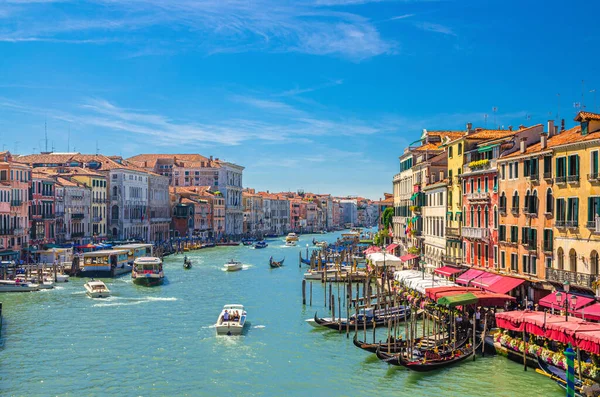 Venice cityscape with Grand Canal waterway. View from Rialto Bridge. Gondolas, boats, vaporettos docked and sailing Canal Grande. Venetian architecture colorful buildings. Veneto Region, Italy.