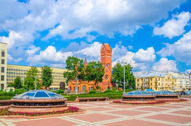 Minsk, Belarus, 26 Temmuz 2020: Azizler Simon ve Helena Roma Katolik Kilisesi veya Minsk şehrinin tarihi merkezinde Bağımsızlık Meydanı 'ndaki Kızıl Kilise, güneşli yaz gününde mavi gökyüzü beyaz bulutları