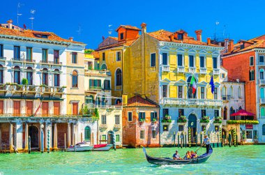 Venedik, İtalya, 13 Eylül 2019: Gondolcu ve turistler, Venedik mimarisi tipik renkli binalarla Grand Canal su yolundaki geleneksel gondolda seyahat ediyorlar.