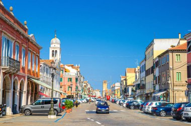 Chioggia, İtalya, 16 Eylül 2019: rengarenk binalar, ana caddede yürüyen insanlar ve arabalar, tarihi şehir merkezinde, yazın mavi gökyüzü arka planı, Veneto Bölgesi