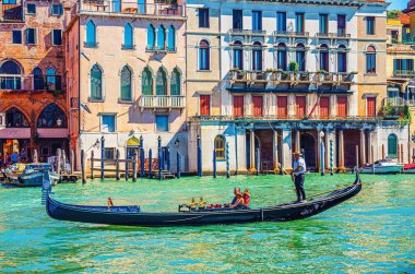 Venedik, İtalya, 13 Eylül 2019: Gondolcu ve turistler, Venedik mimarisi tipik renkli binalarla Grand Canal su yolundaki geleneksel gondolda seyahat ediyorlar.