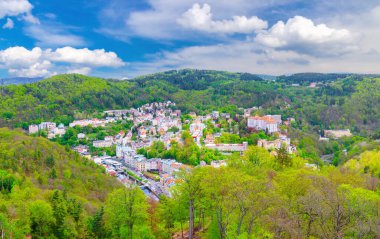 Karlovy Vary şehrinin havadan panoramik manzarası. Tarihi şehir merkezinde renkli binalar ve spa otelleri var. Karlsbad kasabası ve Slavkov Ormanı dağları Panoraması, Çek Cumhuriyeti