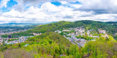 Karlovy Vary şehrinin havadan panoramik manzarası. Tarihi şehir merkezinde renkli binalar ve spa otelleri var. Karlsbad kasabası ve Slavkov Ormanı tepeleri, Çek Cumhuriyeti