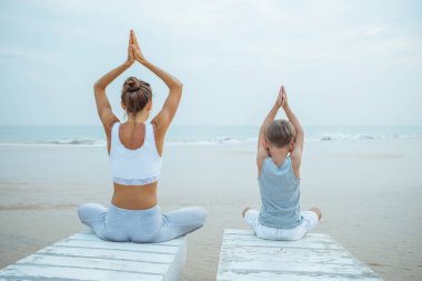 Bir anne ve bir oğlu tropic okyanus sahil, yoga egzersizleri yapıyoruz