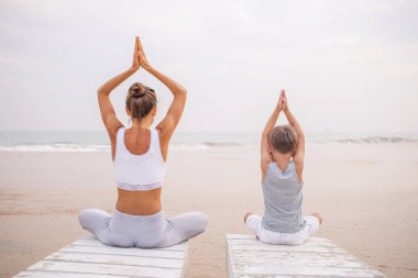 Bir anne ve bir oğlu tropic okyanus sahil, yoga egzersizleri yapıyoruz