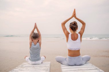 Bir anne ve bir oğlu tropic okyanus sahil, yoga egzersizleri yapıyoruz