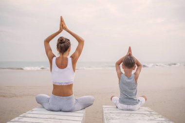 Bir anne ve bir oğlu tropic okyanus sahil, yoga egzersizleri yapıyoruz