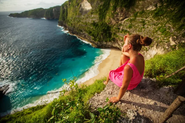 Wanita duduk di tepi tebing dan melihat matahari terbenam, Nus — Stok Foto