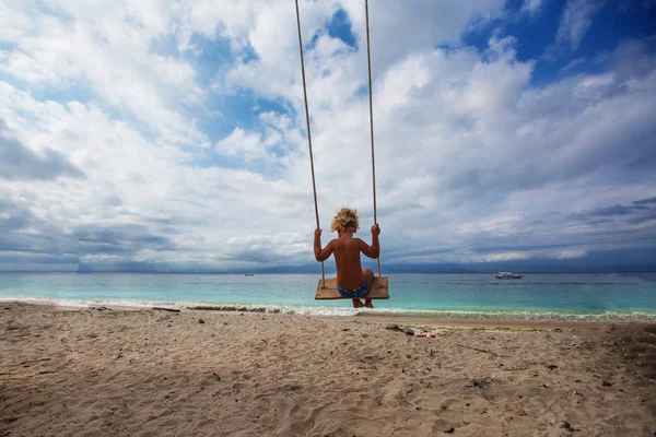 Bagian belakang ayunan anak laki-laki bermain di pantai — Stok Foto