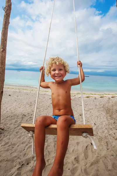 La parte de atrás de los chicos columpios están jugando en la playa — Foto de Stock