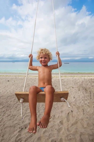 La parte de atrás de los chicos columpios están jugando en la playa — Foto de Stock