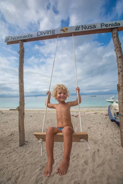 La parte de atrás de los chicos columpios están jugando en la playa — Foto de Stock