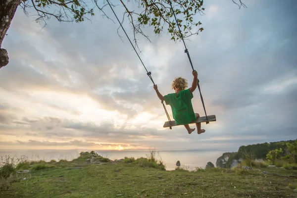 Bak på pojkarna gungor spelar på stranden — Stockfoto