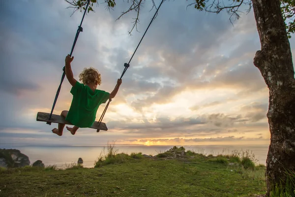 Bak på pojkarna gungor spelar på stranden — Stockfoto